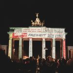 Brandenburger Tor in Berlin bei Nacht beleuchtet beim Festival of Lights zum Thema 35 Jahre Mauerfall.