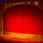 Theaterbühne mit geschlossenem schwerem rotem Samtvorhang in einem Barock-Theater in Berlin.