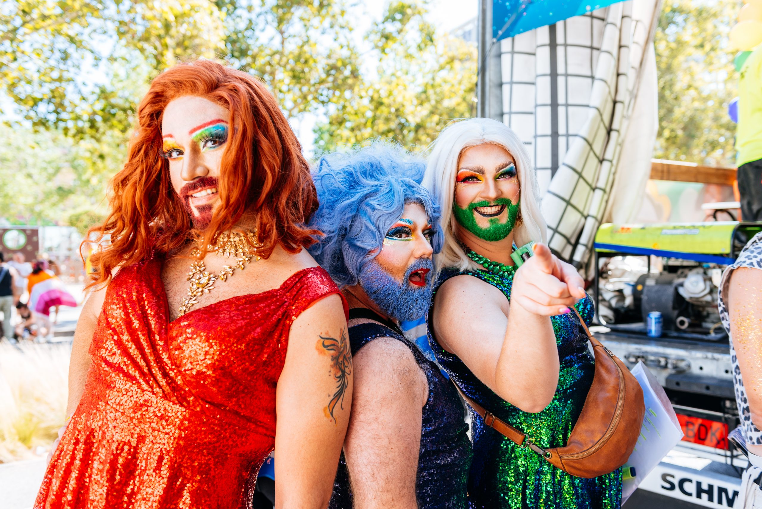 Happy group of Drag Queens standing together smiling during gay pride carnival in street