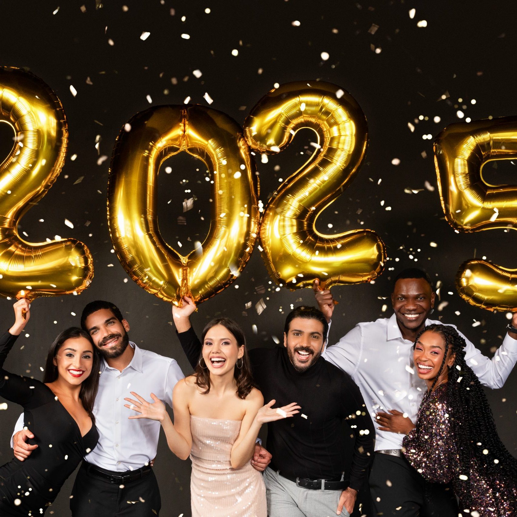 Happy multiracial people three loving millennial couples wearing nice outfits celebrating new year 2025 together on black background, holding golden number baloons and smiling at camera